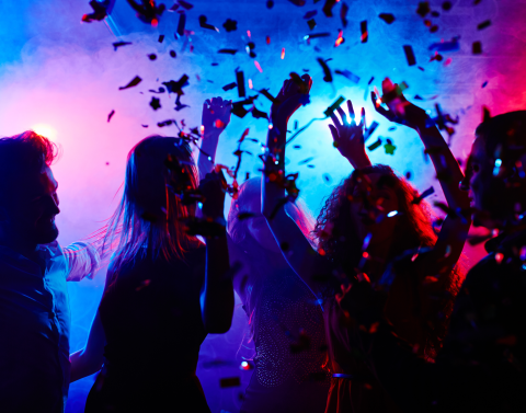 People dancing in a nightclub with confetti falling around them